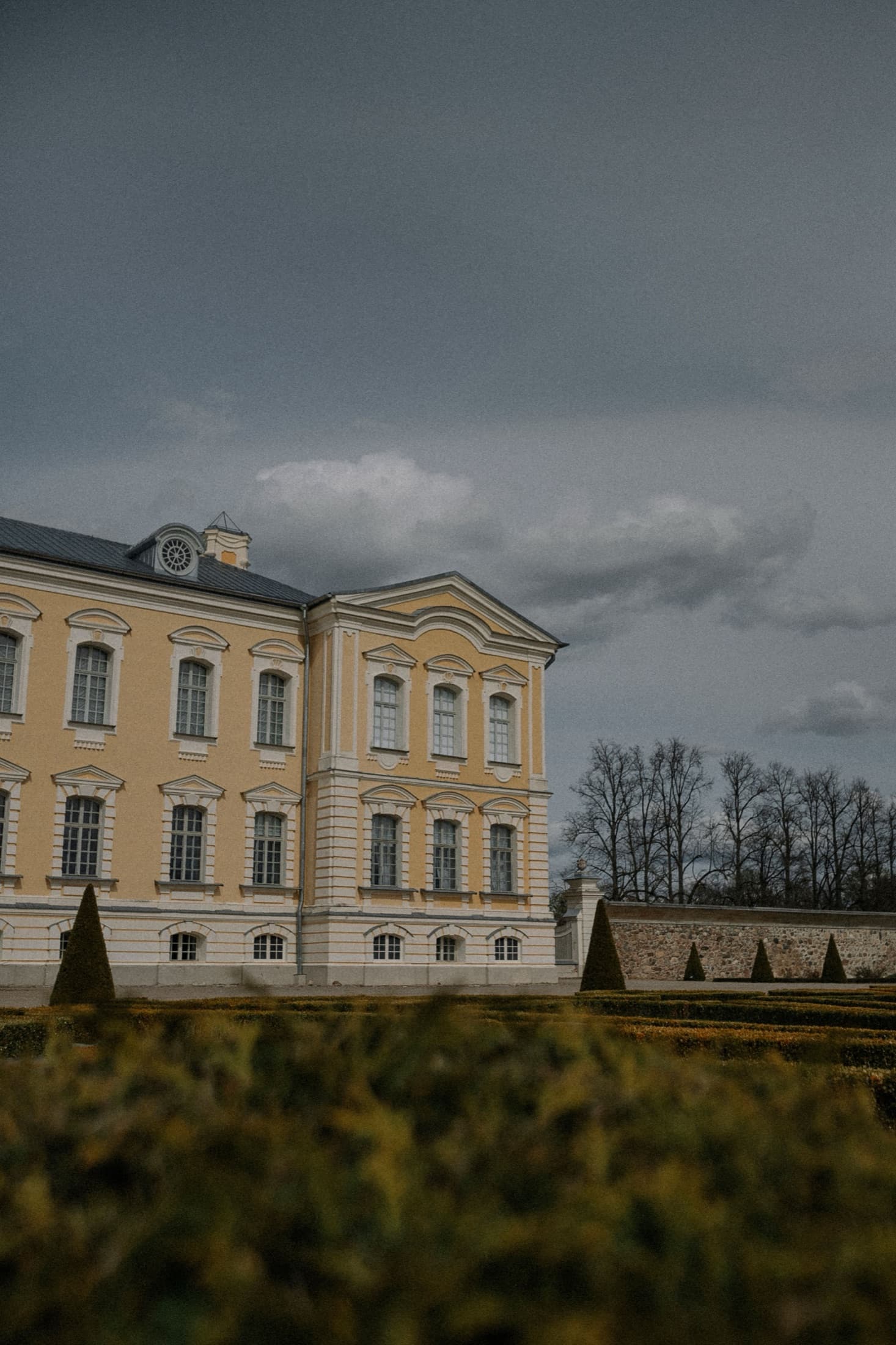 Rundale Palace's grand Baroque facade beneath a dramatic sky, surrounded by gardens