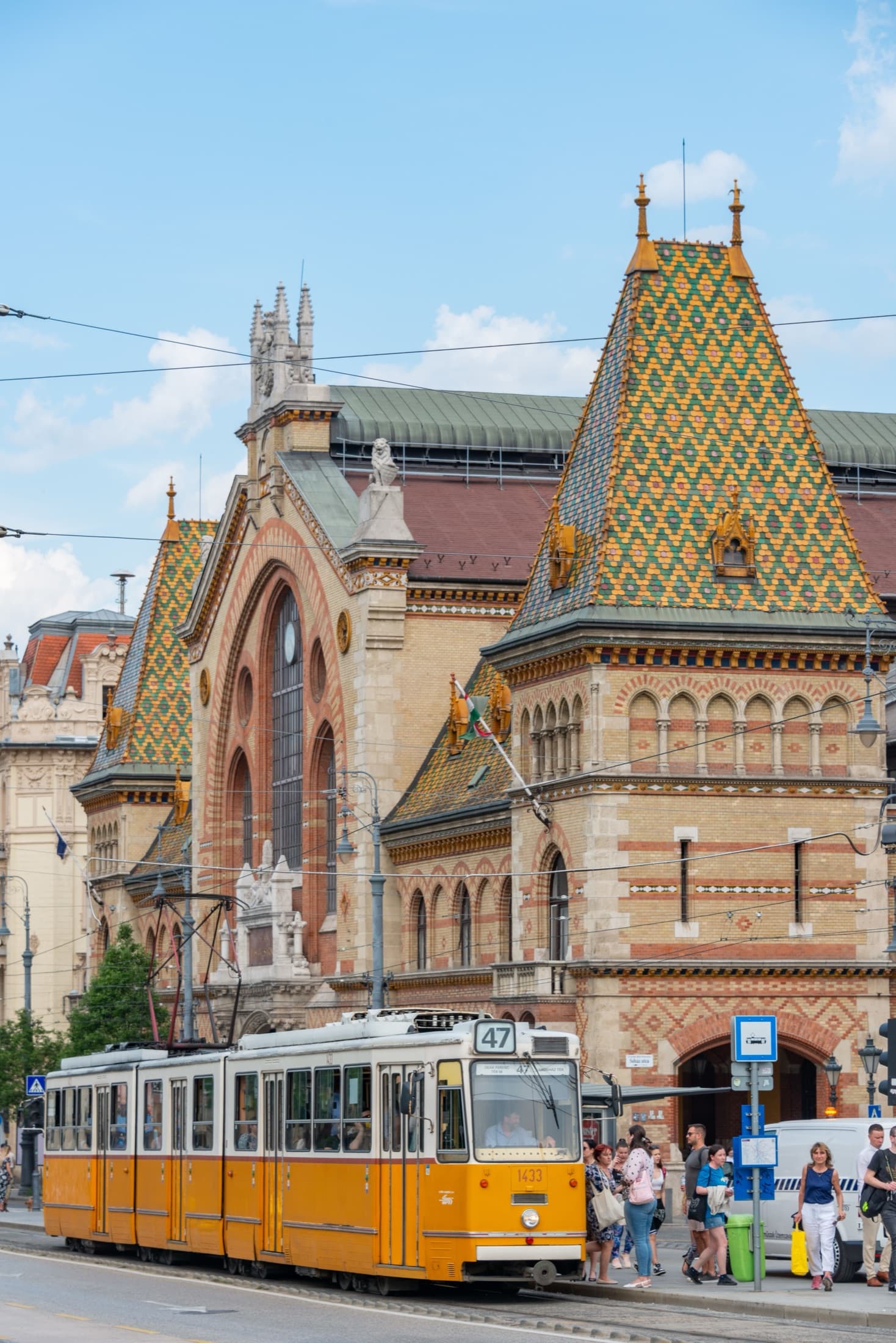 A yellow tram passing the Central Market Hall in Budapest