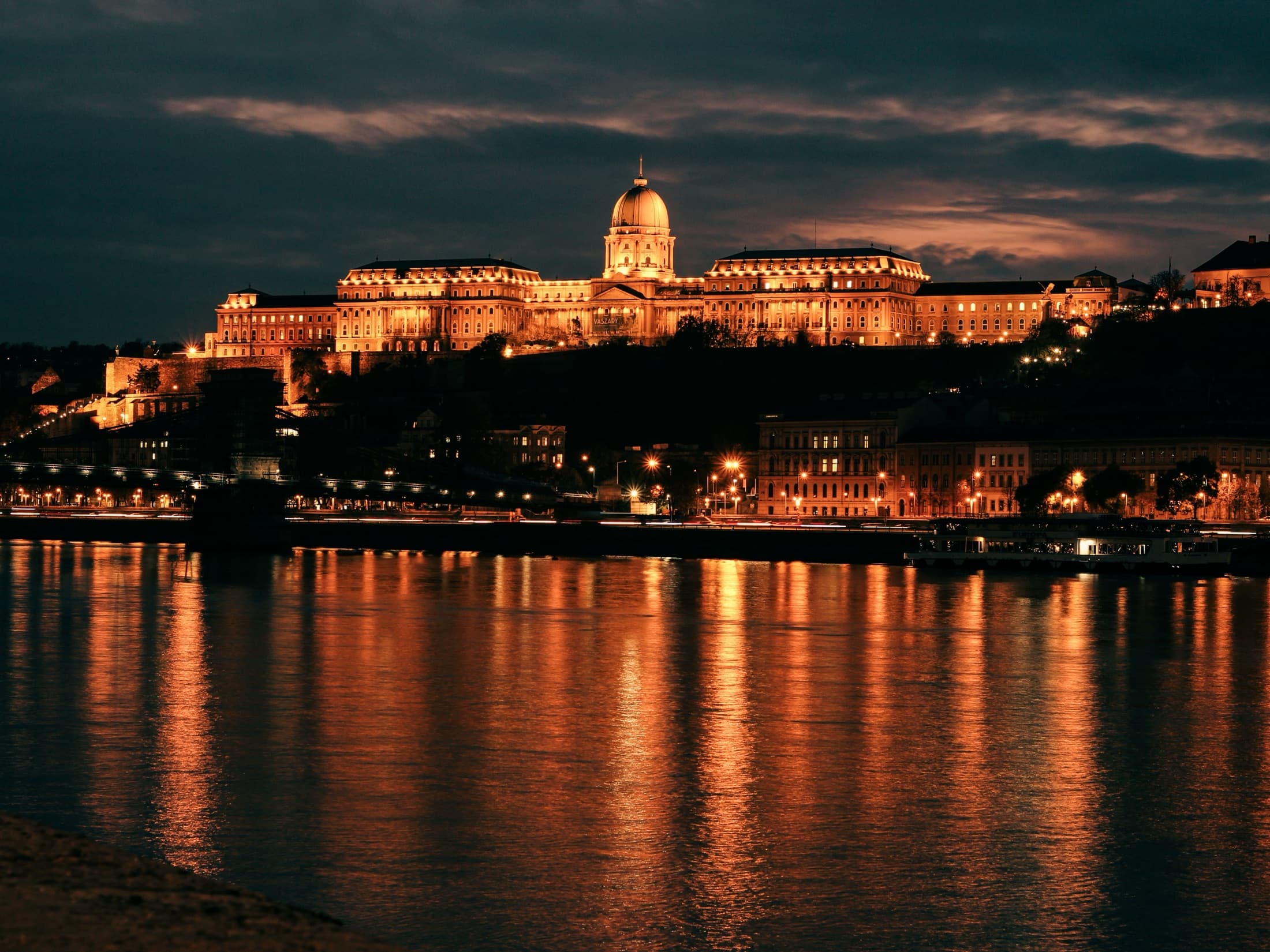 Buda Castle glowing at night, reflecting on the Danube River in Budapest