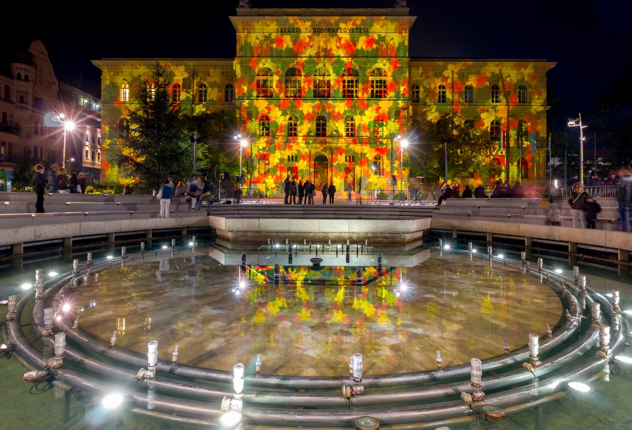 The Rectorate building of the University of Szeged on Dugonics Square at night, with its illuminated musical fountain