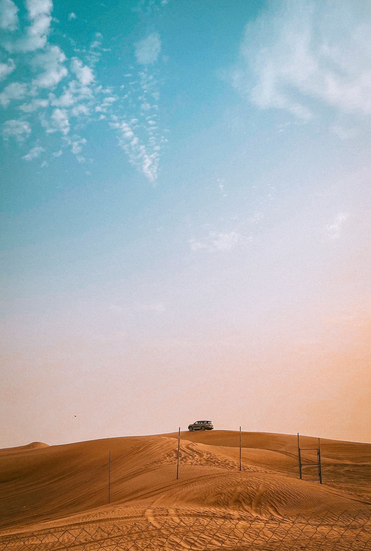 A desert safari vehicle crossing Dubai's sand dunes during sunset