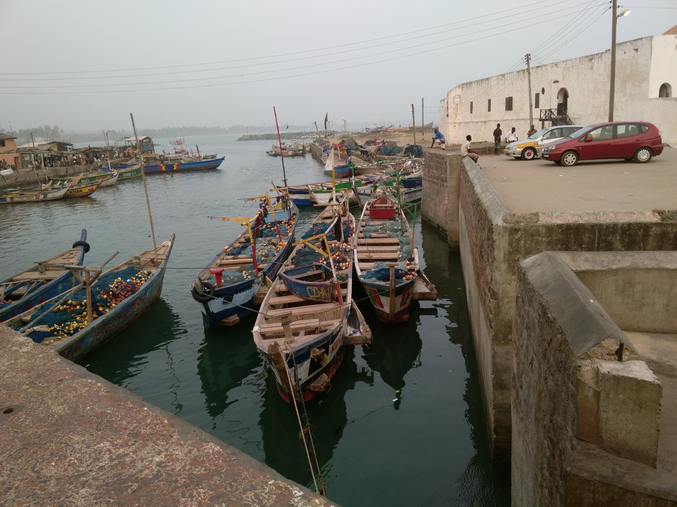 Traditional fishing canoes moored at the dock beside Elmina Castle