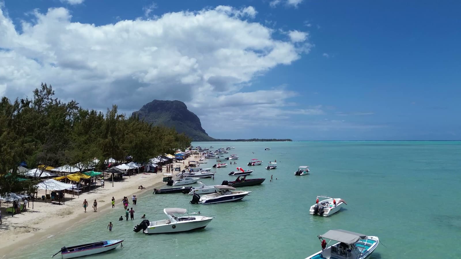Drone footage of a tropical beach with boats and the Le Morne Brabant mountain, Mauritius