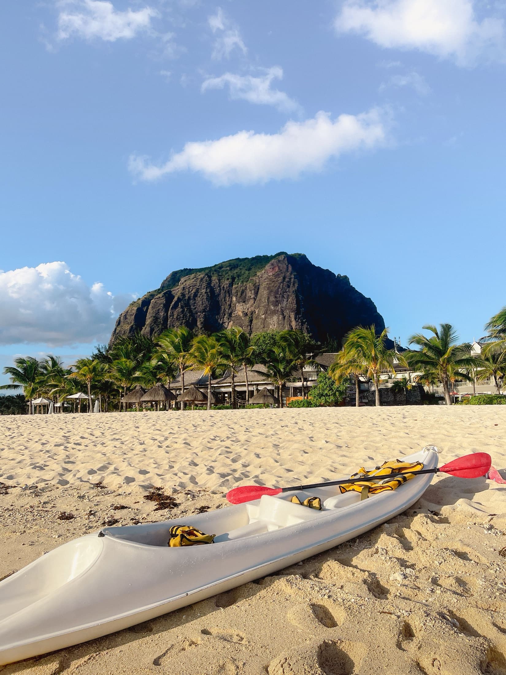 Serene beach with a canoe, palm trees, and Le Morne Brabant mountain in the background, Mauritius