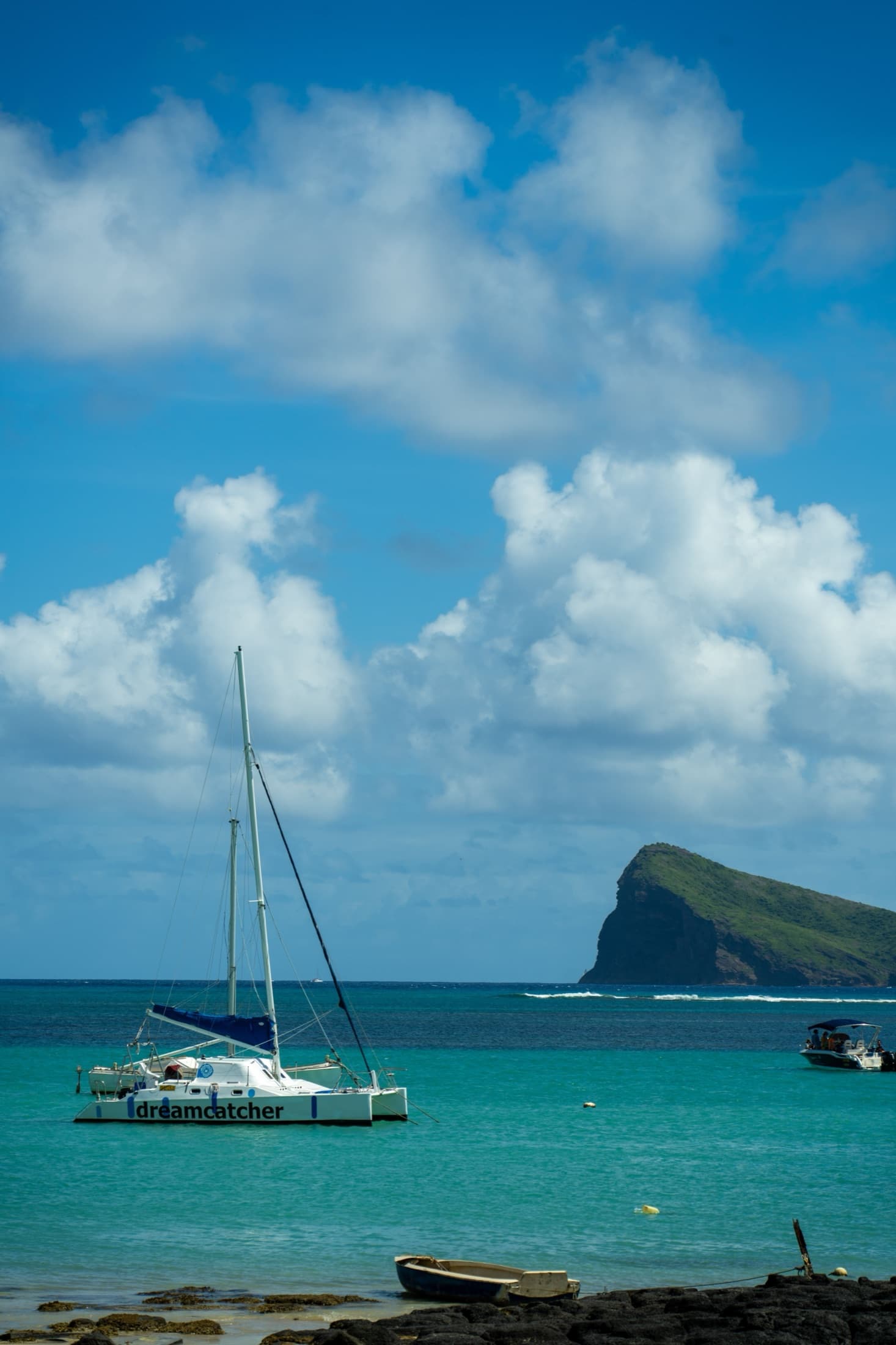 A catamaran sailing in turquoise lagoon waters near an island, Mauritius