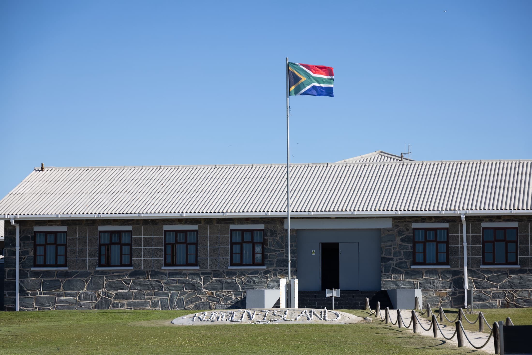 The Robben Island Museum building with the South African flag under a clear blue sky