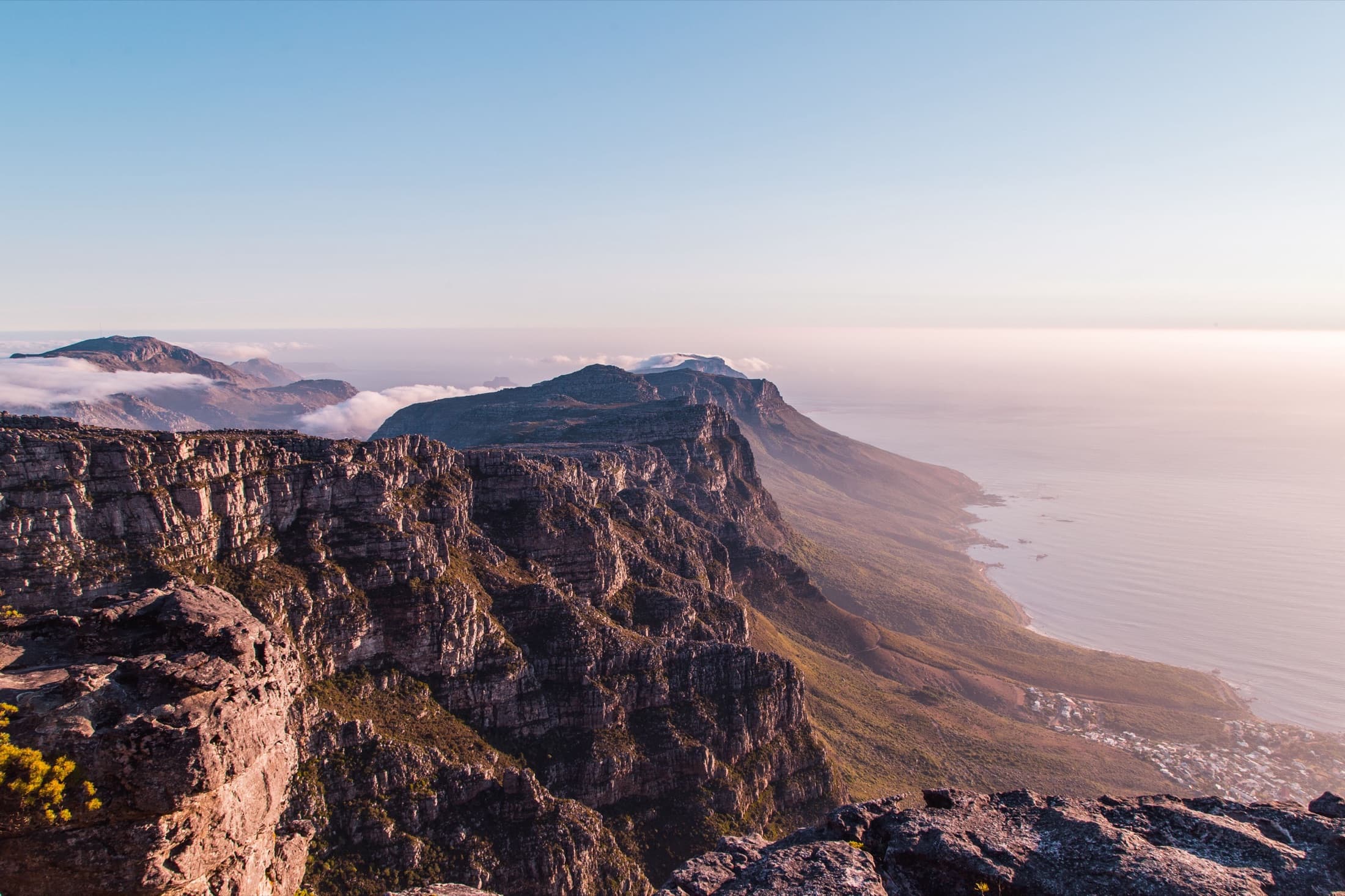 A ground-level view of Table Mountain's dramatic cliffs above the ocean at sunset